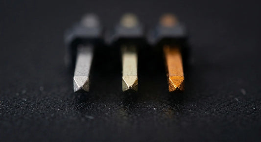 An close-up photograph comparing three different connector platings side-by-side: dull silver tin, pale 15μ" gold, and rich, deep 30μ" gold, highlighting the tonal differences in the gold thickness.