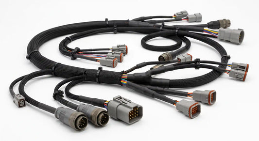 A complete industrial engine wiring harness laid out on a white studio background, showcasing complex branching, braided sleeving, and heavy-duty sealed connectors.